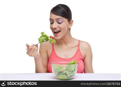 Close-up of beautiful woman eating lettuce over white background
