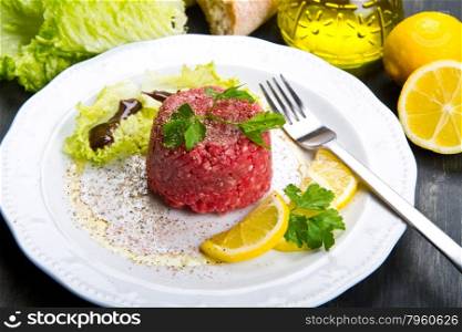 Close up of beef tartar with fresh salad and lemon slice