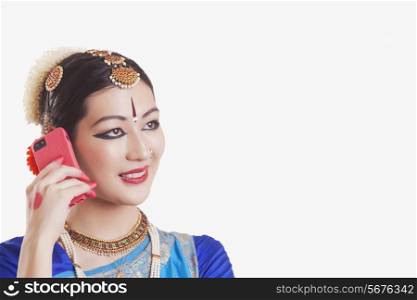 Close-up of Bharatanatyam dancer using mobile phone over white background