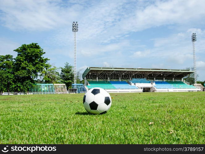 close up of black and white soccer on field with stadium background