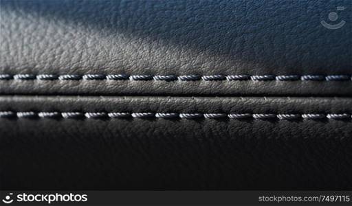 Close up of black leather detail with light and shade of a modern car interior