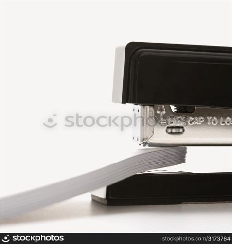 Close up of black stapler on white background stapling paper.