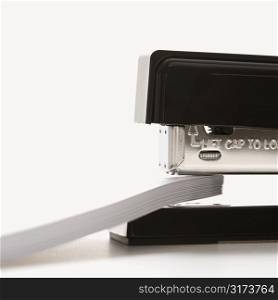 Close up of black stapler on white background stapling paper.