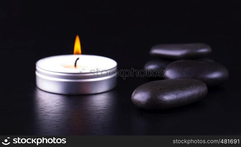 Close-up of black stones and candle on black background