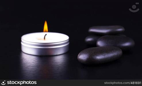 Close-up of black stones and candle on black background