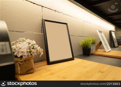 Close up of blank photo or picture frame on shelf in modern cozy loft interior design decoration room. Workplace or co-working space.