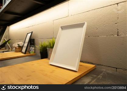Close up of blank photo or picture frame on shelf in modern cozy loft interior design decoration room. Workplace or co-working space.