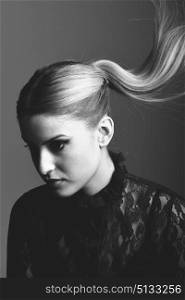 Close-up of blond woman wearing shirt with a ponytail. Studio shot. Black and white photograph