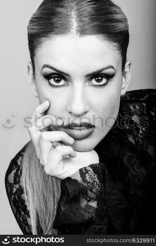 Close-up of blond woman wearing shirt with a ponytail. Studio shot. Girl with her hand near her mouth. Black and white photograph