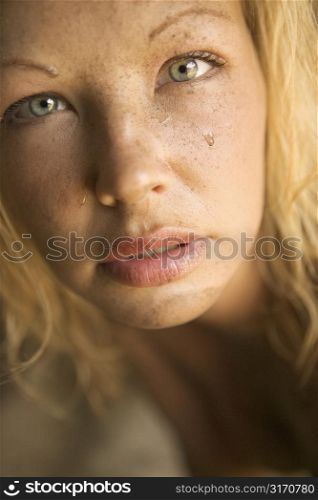 Close-up of blond womans muddy face looking at viewer.