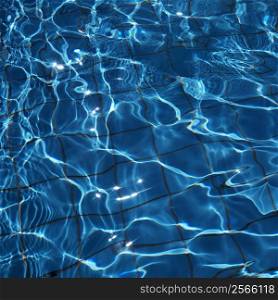Close-up of blue reflective rippling water with grid pattern in bottom of pool.