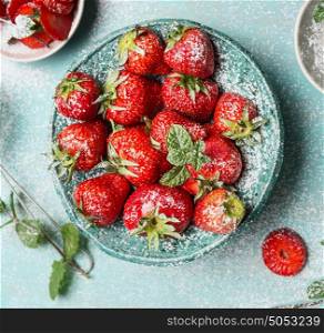Close up of bowl with Strawberries on light blue rustic background, top view