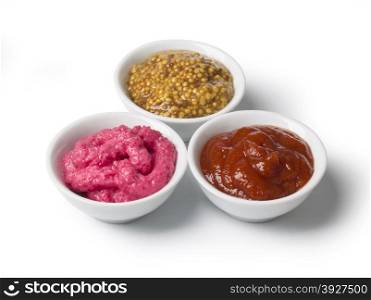 close up of bowls of tomato ketchup and mustard and barbecue sauce with clipping path