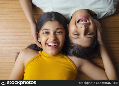 Close-up of boy and girl lying down on wooden floor 
