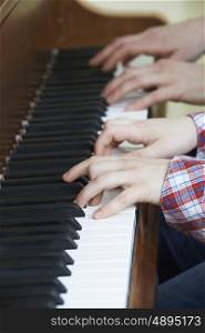 Close Up Of Boy Playing Piano Duet With Teacher