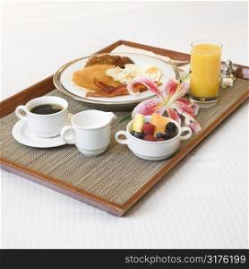 Close-up of breakfast tray laying on white bed.