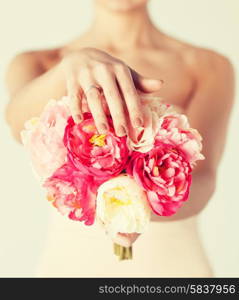 close up of bride with bouquet of flowers and wedding ring.