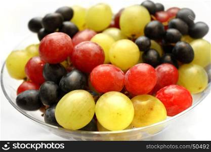 Close up of bright assortment tasty ripe grapes in a glass plate on white background