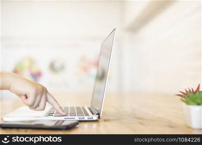 Close-up of business female working hands typing on a laptop keyboard with smartphone in coffee shop like the background