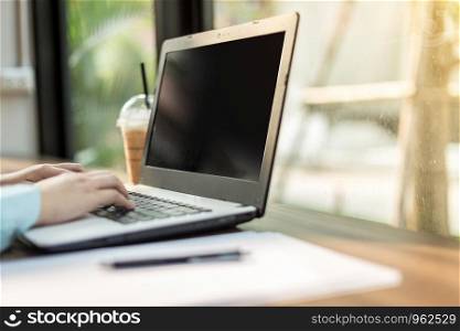 Close-up of business female working with laptop make a note document and smartphone in coffee shop like the background.
