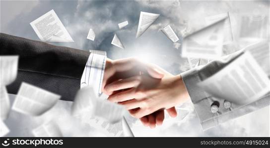 Close up of business handshake with papers at background