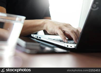 Close up of business man hand working on laptop computer on wooden desk as concept