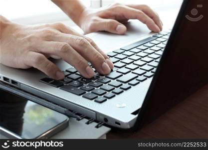 Close up of business man hand working on laptop computer on wooden desk as concept