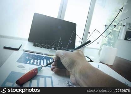 close up of business man hand working on laptop computer with business graph information diagram on wooden desk as concept 