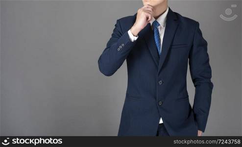 Close up of business man in blue suit is thinking on gray background