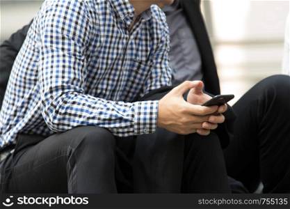 close up of business man's hand holding the smart phone and checking the news and email while sitting outside office