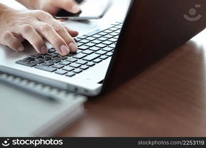 Close up of business man working on laptop computer on wooden desk as concept