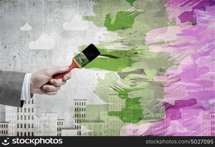 Close up of business person hand holding paint brush. Add some color