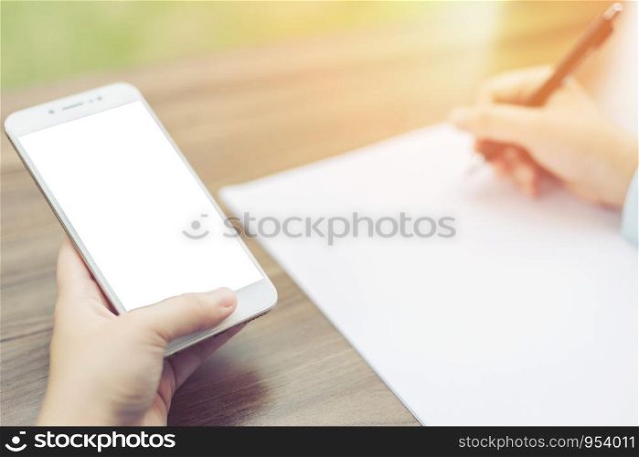 Close-up of Business woman makes a note at business document and smartphone.