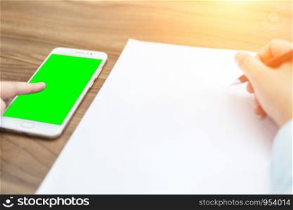Close-up of Business woman makes a note at business document and smartphone.