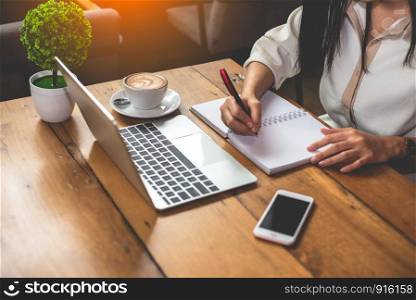 Close up of business woman working with documents and laptop in office. Business and Lifestyles concept. Entrepreneur and Freelance theme. Selective focus on coffee cup