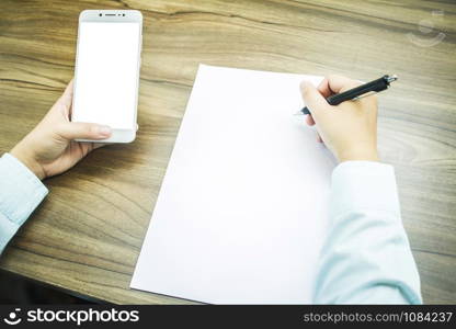 Close-up of Business woman working with smartphone and make a note of document in coffee shop like the background.