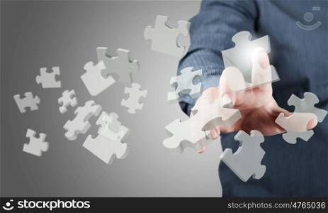 Close up of businessman&#39;s hand touching abstract puzzle piece