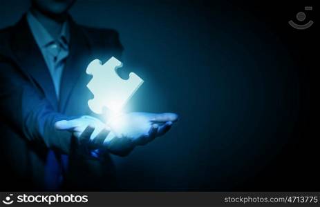 Close up of businessman&amp;#39;s hand holding puzzle piece