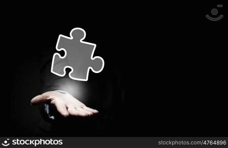 Close up of businessman&amp;#39;s hand holding puzzle piece