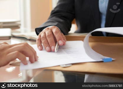 Close-up of businessman examining business contract and signing it at the office desk. Business people signing a contract