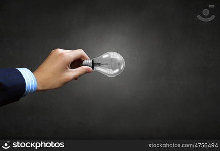 Close up of businessman hand holding glass light bulb. Bulb in hand