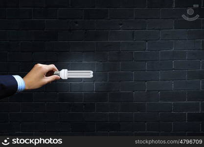 Close up of businessman hand holding glass light bulb. Bulb in hand