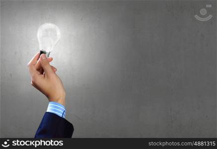 Close up of businessman hand holding glass light bulb. Bulb in hand