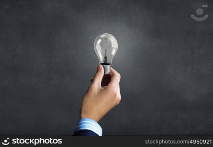 Close up of businessman hand holding glass light bulb. Bulb in hand