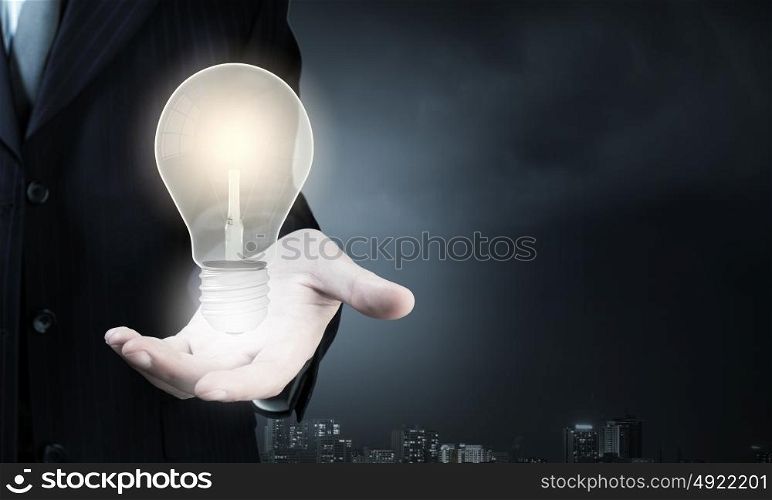Close up of businessman hand holding light bulb. Light bulb in hand
