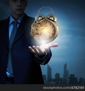 Close up of businessman hand holding old alarm clock. Time management