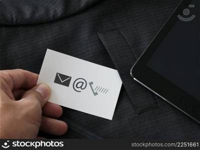 close up of businessman hand picking business card icon contact us concept from the pocket of gray suit jacket background