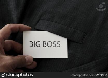 close up of businessman hand picking business card reading BIG BOSS from the pocket of gray suit jacket background