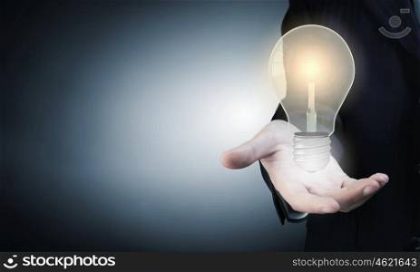 Close up of businessman hand showing light bulb. Bright idea