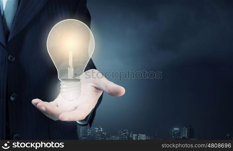 Close up of businessman hand showing light bulb. Bright idea